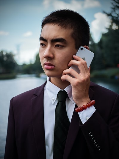 身穿黑色西装夹克的男子手持银色iphone 6